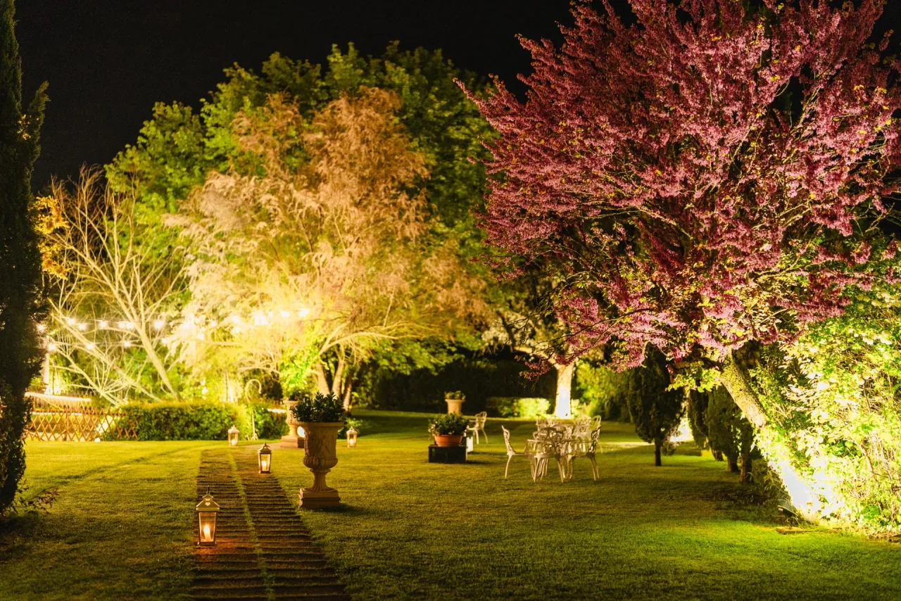 The gardens of Tenuta I Massini at night, illuminated by lanterns and warm lights